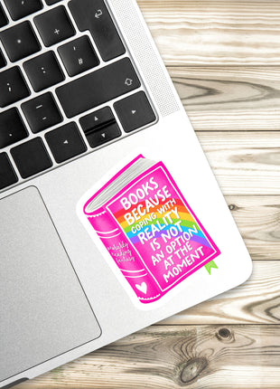 A sticker with a colorful book illustration is placed on a laptop keyboard, with a wooden surface in the background.