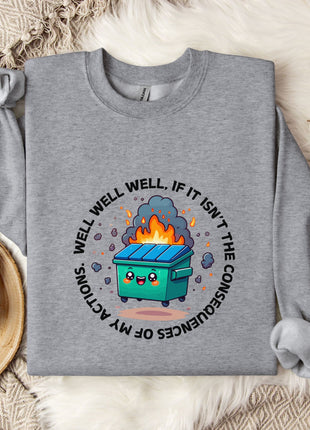 a gray sweatshirt with a graphic design depicting a fire-breathing trash can surrounded by flames and smoke. The sweatshirt is placed on a bed with a white blanket and a white mug.