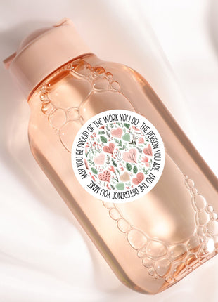 A pink bottle with a white label featuring a floral design and text.