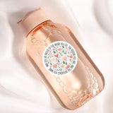A pink bottle with a white label featuring a floral design and text.