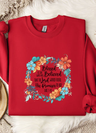 A red sweater with a floral design and text printed on it, along with a mug, a white mug, and some white flowers on a white fur rug.