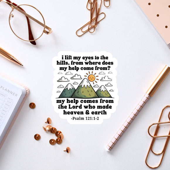 a sticker with a Bible verse and a mountain landscape, along with a pair of glasses, a pen, and some office supplies.