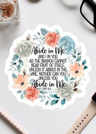 a sticker with a floral design and text, surrounded by various office supplies such as a watch, pen, and glasses.