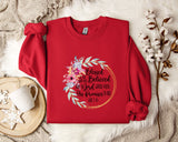 A red sweater with a floral design and text printed on it, placed on a white fur rug.