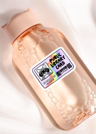A clear glass bottle with a label that reads "Public Library Card" and features a cartoon raccoon.