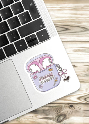 A sticker of a pair of pink earbuds with a cartoon character on a laptop keyboard.