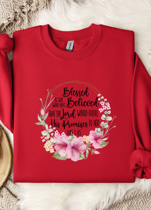 A red sweater with a floral design and text printed on it, placed on a white fur rug.