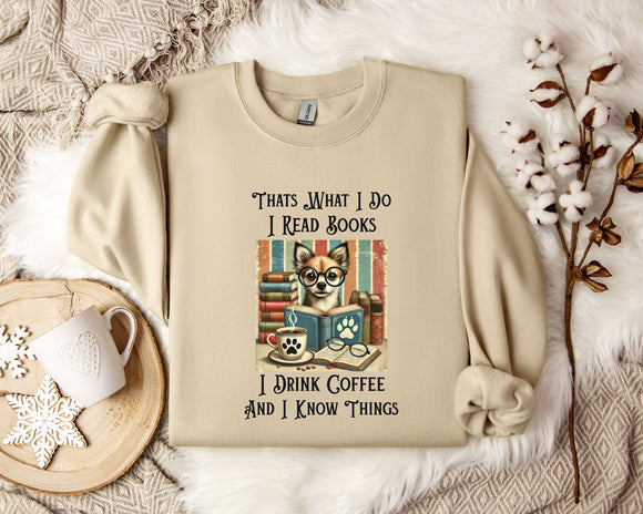 A beige sweatshirt with a printed design of a cat wearing glasses and surrounded by books, along with text that says 