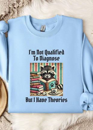 A light blue sweatshirt with a graphic design of a raccoon reading books and the text "I'm Not Qualified To Diagnose But I Have Theories" printed on it.