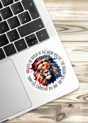 A sticker with an image of a lion is placed on the edge of a laptop keyboard.