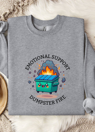 a gray sweatshirt with a graphic design depicting a dumpster with flames coming out of it, accompanied by the text "Emotional Support Dumpster Fire".