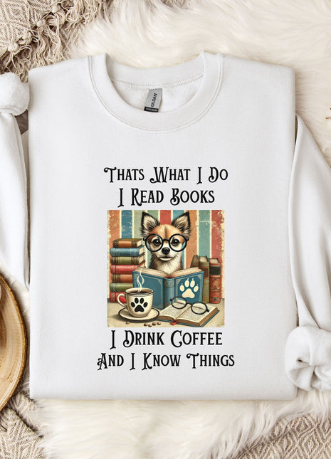 A white t-shirt with a printed design of a cat and books, along with text that says "Thats what I do I read books I drink coffee and I know things".