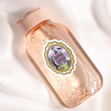 A pink bottle with a label featuring a castle and bats, along with a decorative border.