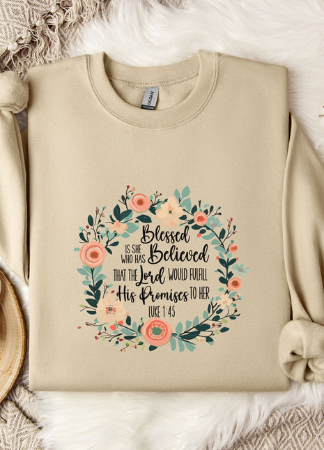 A beige sweatshirt with a floral design and text printed on it, along with a mug, a branch of cotton bolls, and a snowflake.