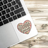 A laptop with a heart-shaped sticker on the palm rest, featuring a message about a girl who needs snacks.