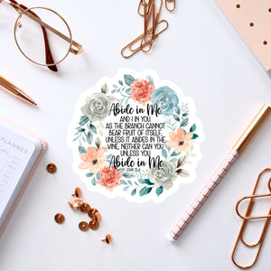 a sticker with a floral design, surrounded by various office supplies such as pens, a notebook, and a pair of glasses.