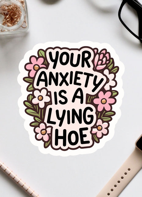 a sticker with the text "Your anxiety is a lying hoe" surrounded by flowers.