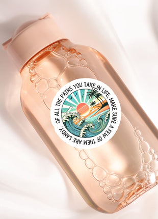 A pink bottle with a sticker featuring a beach scene and the text "Of all the paths you take in life, make sure you take a few good ones".