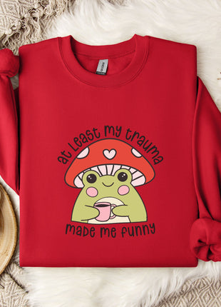 A red sweater with a mushroom graphic and text, placed on a white fur rug, along with a mug, a snowflake, and some white flowers.