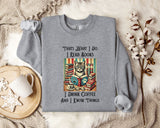 A gray sweatshirt with a printed design of a cat surrounded by books and coffee cups, along with text that reads "Thats what I do I read books I drink coffee and I know things".