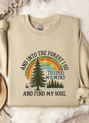 A beige sweatshirt with a graphic design of a forest and a rainbow, along with the text "AND INTO THE FOREST I GO TO LOSE MY MIND AND FIND MY SOUL".