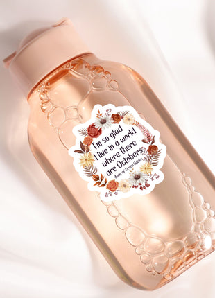 A pink bottle with a floral label, containing a clear liquid, is shown against a white background.