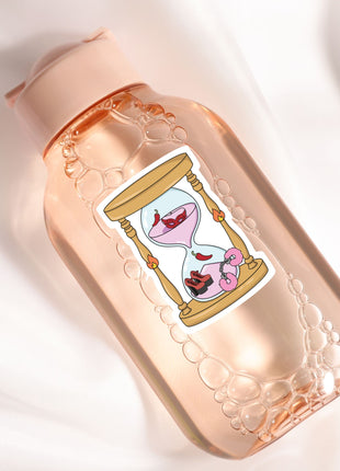 A pink bottle with a label featuring a cartoon illustration of a sand timer with a pink flower inside.