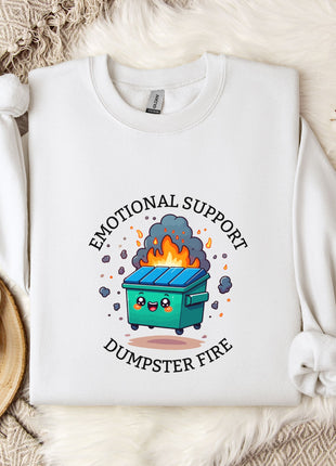 a white sweatshirt with a graphic design depicting a fire-breathing dumpster, accompanied by the text "Emotional Support Dumpster Fire".
