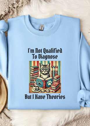A light blue sweatshirt with a printed design of a cat surrounded by books and a cup of coffee, along with the text "I'm Not Qualified To Diagnose But I Have Theories".