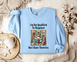 A light blue sweatshirt with a printed design of a cat surrounded by books and a cup of coffee, along with the text "I'm Not Qualified To Diagnose But I Have Theories".