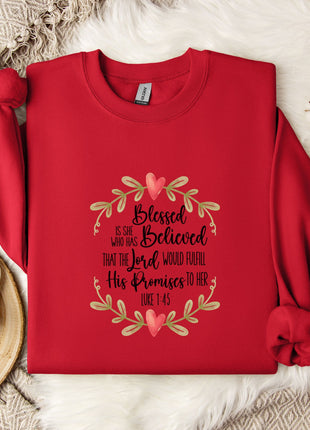 A red sweater with a floral design and text printed on it, along with a mug, a white mug, and some white flowers on a white fur rug.