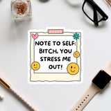 a sticker with a humorous message, surrounded by various office supplies and a pair of glasses on a white surface.