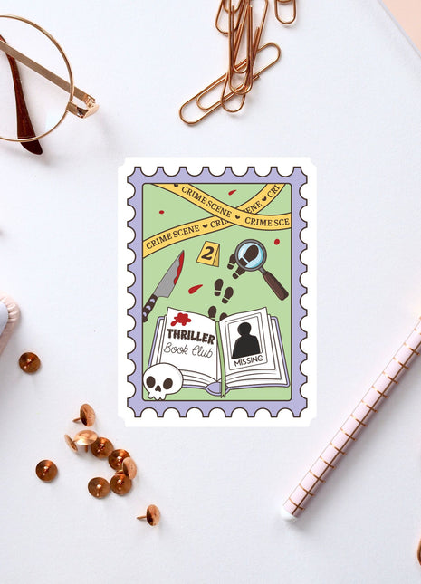 a postage stamp with a cartoon illustration of a book club, a magnifying glass, and various crime-related items, surrounded by office supplies such as pens, paper clips, and a notebook.