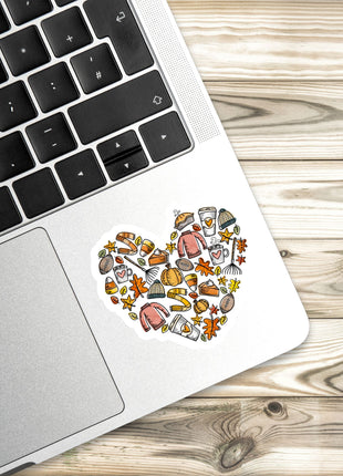 a laptop with a heart-shaped sticker on the palm rest, placed on a wooden surface.