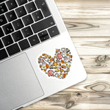 a laptop with a heart-shaped sticker on the palm rest, placed on a wooden surface.