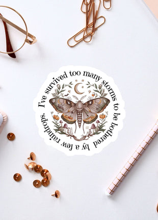 a sticker with a butterfly design, surrounded by various office supplies such as pens, a notebook, and a pair of glasses.