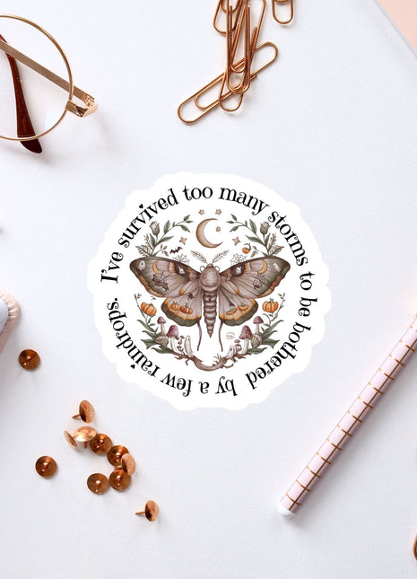 a sticker with a butterfly design, surrounded by various office supplies such as pens, a notebook, and a pair of glasses.