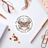 a sticker with a butterfly design, surrounded by various office supplies such as pens, a notebook, and a pair of glasses.
