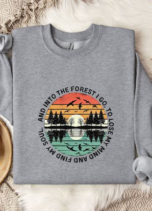A gray sweatshirt with a graphic design depicting a sunset over a forest, along with the text "And into the forest I go, to lose my mind and find my soul".