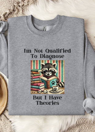 a gray sweatshirt with a graphic design of a raccoon surrounded by books, along with text that reads "I'm Not Qualified To Diagnose But I Have Theories".