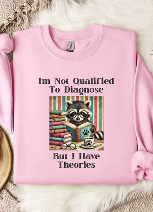 A pink sweatshirt with a graphic design of a raccoon reading a book, accompanied by text that reads "I'm Not Qualified To Diagnose But I Have Theories".