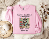 A pink sweatshirt with a graphic design of a raccoon reading a book, accompanied by text that reads "I'm Not Qualified To Diagnose But I Have Theories".
