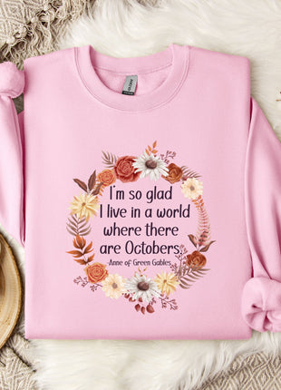 A pink sweatshirt with a floral wreath design and a quote printed on it, placed on a white fur rug.
