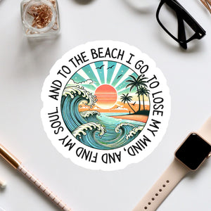 A sticker with a beach scene and a sunset, surrounded by various office supplies and a pair of glasses.