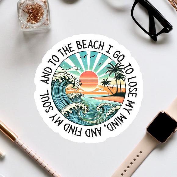 A sticker with a beach scene and a sunset, surrounded by various office supplies and a pair of glasses.