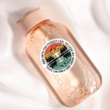 A pink bottle with a sticker featuring a sunset landscape and silhouettes of trees.