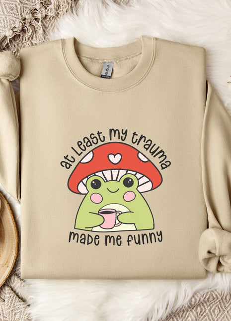 a beige sweatshirt with a mushroom character and text printed on it, along with a mug and some flowers on a bed.