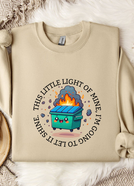 a beige sweatshirt with a graphic design depicting a trash can with flames coming out of it, surrounded by a circular design with the text "This little light of mine is going to blow up".