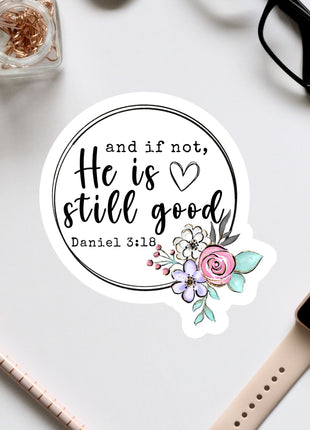 a sticker with a quote and a floral design, surrounded by various office supplies such as a watch, pen, and glasses.