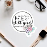a sticker with a quote and a floral design, surrounded by various office supplies such as a watch, pen, and glasses.